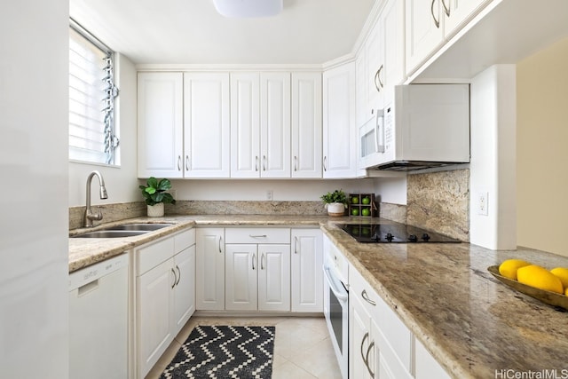 kitchen featuring white appliances, light stone countertops, light tile patterned flooring, sink, and white cabinetry