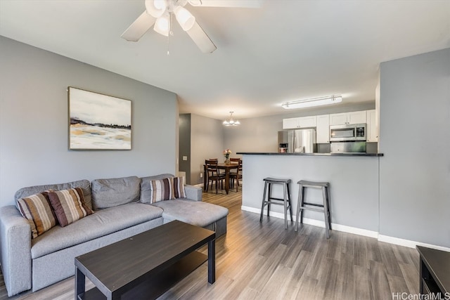 living room featuring hardwood / wood-style floors and ceiling fan with notable chandelier