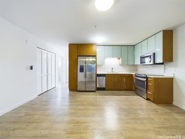 kitchen featuring stainless steel appliances, sink, and light wood-type flooring