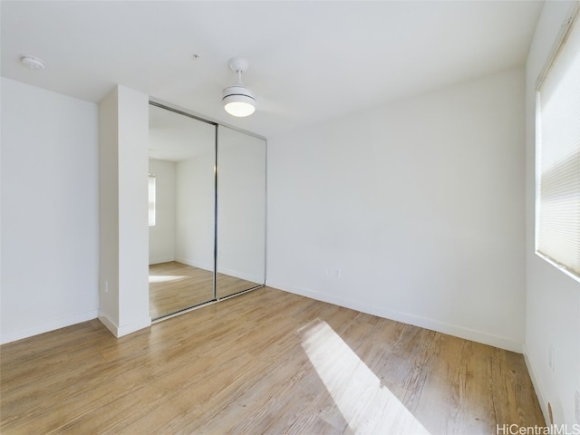 unfurnished bedroom with light wood-type flooring and a closet