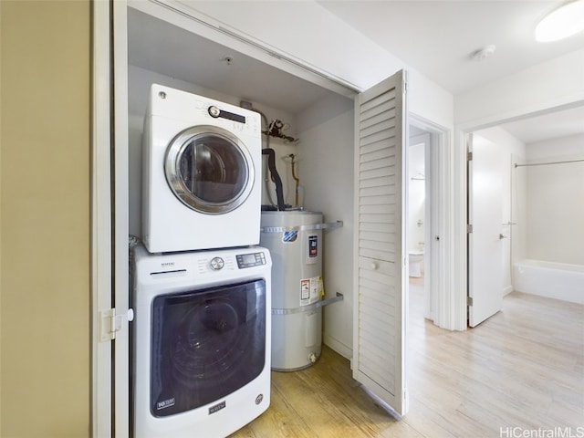 washroom with light hardwood / wood-style floors, water heater, and stacked washer and clothes dryer