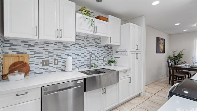 kitchen featuring stainless steel dishwasher, light tile patterned floors, tasteful backsplash, light stone counters, and white cabinetry