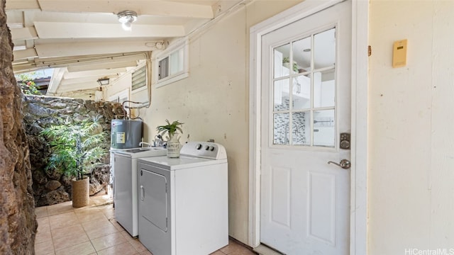 clothes washing area with electric water heater, washing machine and dryer, and light tile patterned floors