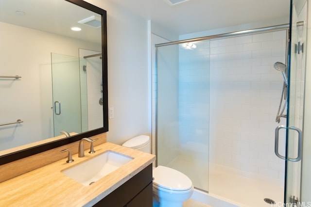 bathroom featuring toilet, vanity, and a shower with door