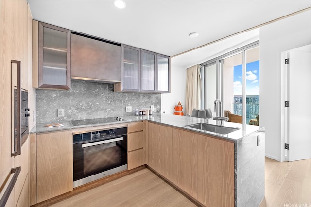 1000 Auahi St Unit 4106, Honolulu, HI 96814 - kitchen featuring oven, a sink, light wood-style floors, a peninsula, and decorative backsplash