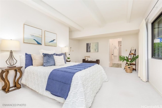 carpeted bedroom with beamed ceiling and connected bathroom