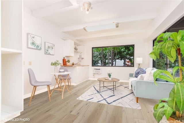 sitting room with beam ceiling and light wood-type flooring