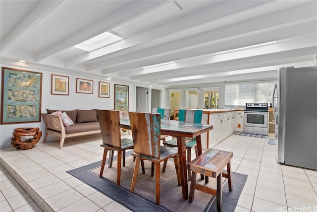 dining room with beamed ceiling, a skylight, and light tile patterned floors