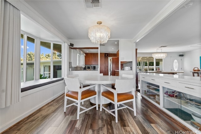 dining space featuring dark wood-type flooring, crown molding, and a notable chandelier