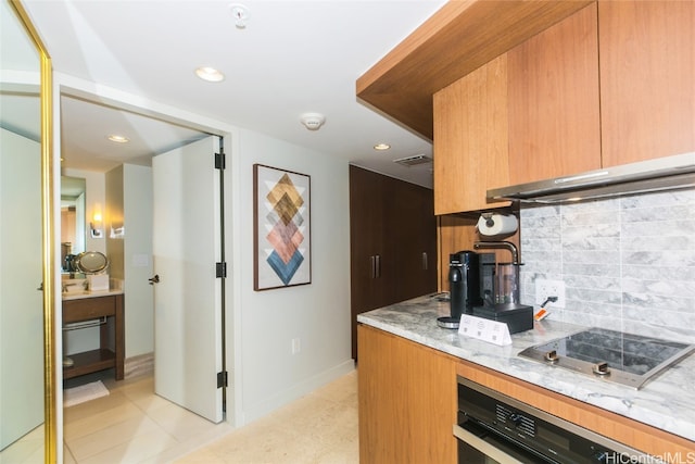 kitchen with stovetop, decorative backsplash, stainless steel oven, light stone countertops, and light tile patterned floors