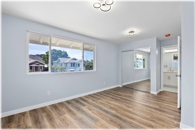 unfurnished bedroom with sink, light hardwood / wood-style flooring, ensuite bathroom, and a closet