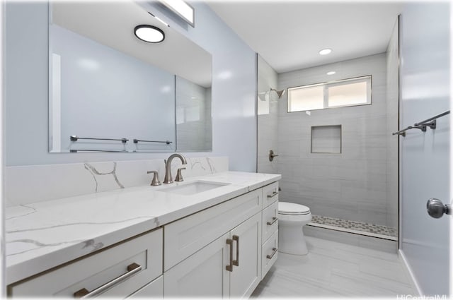 bathroom with vanity, toilet, and tiled shower