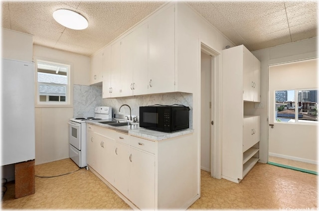 kitchen featuring white electric range, a healthy amount of sunlight, and white cabinets