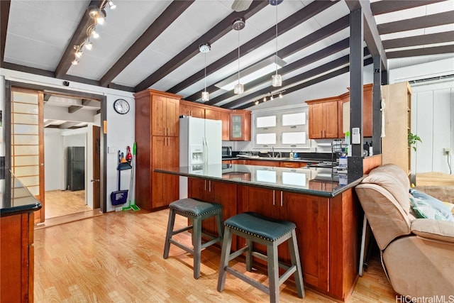 kitchen featuring light hardwood / wood-style floors, white fridge with ice dispenser, kitchen peninsula, and vaulted ceiling with beams