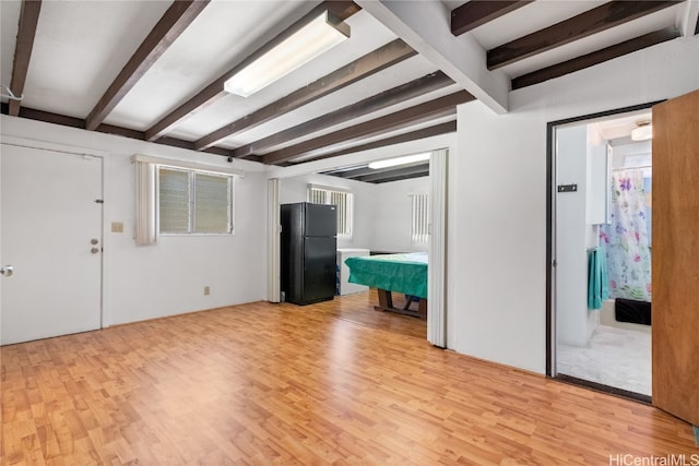 unfurnished living room with light hardwood / wood-style floors and beamed ceiling