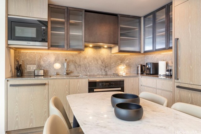 kitchen featuring decorative backsplash, black appliances, sink, and a breakfast bar area