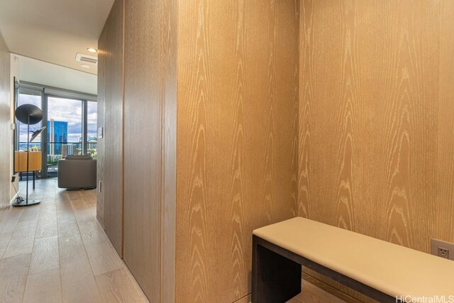 hallway featuring light hardwood / wood-style flooring and wood walls