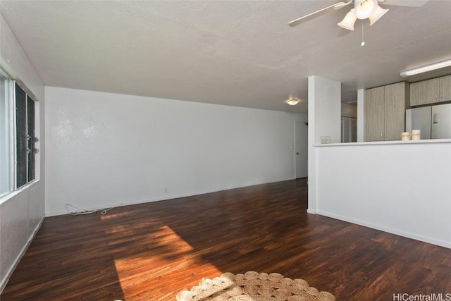 unfurnished living room with ceiling fan, dark wood-type flooring, and a textured ceiling