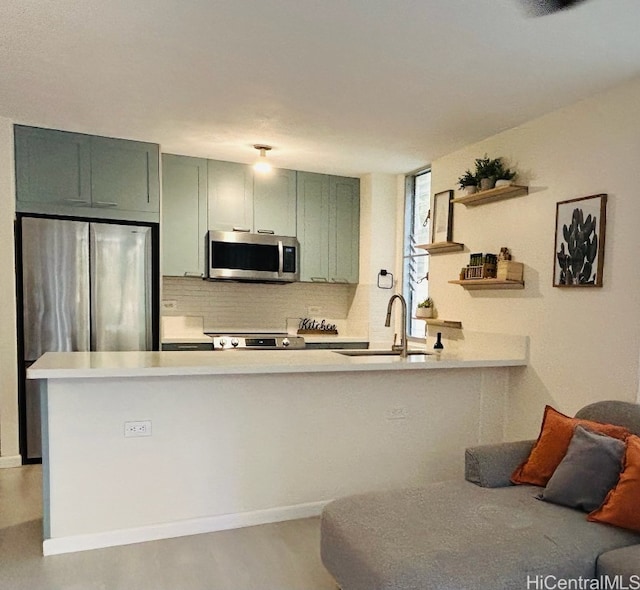 kitchen with green cabinets, kitchen peninsula, sink, and appliances with stainless steel finishes