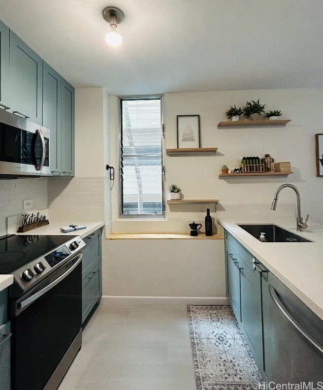 kitchen featuring appliances with stainless steel finishes, tasteful backsplash, green cabinetry, and sink