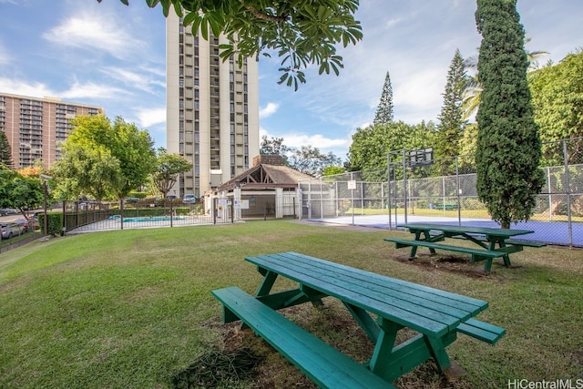 view of community with fence, a pool, a lawn, and a gazebo