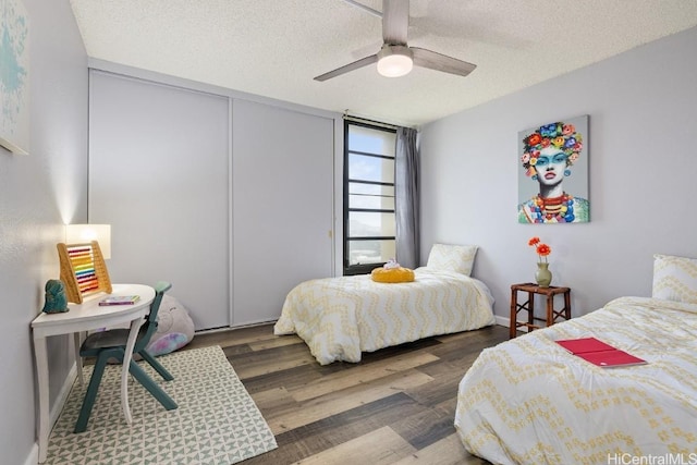 bedroom featuring a textured ceiling, a closet, dark wood finished floors, and a ceiling fan