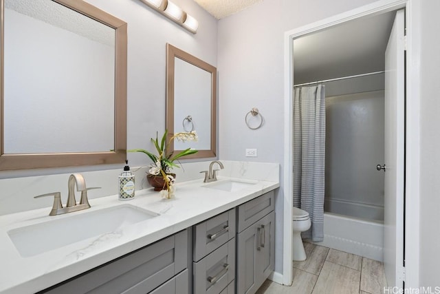 bathroom featuring shower / bath combo with shower curtain, a sink, toilet, and double vanity