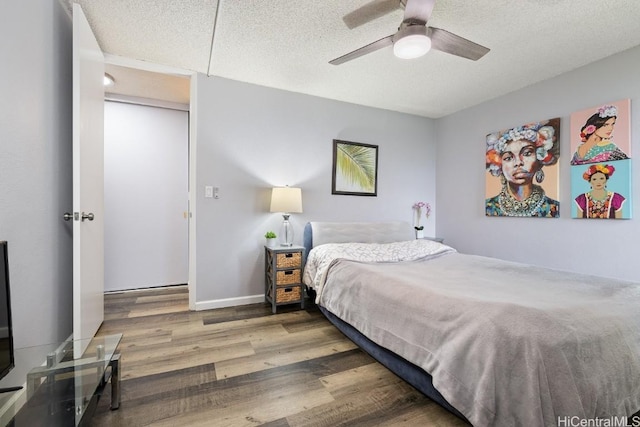 bedroom featuring a ceiling fan, a textured ceiling, baseboards, and wood finished floors