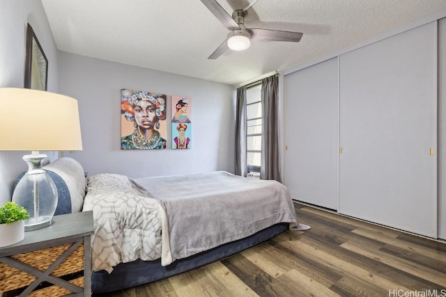 bedroom featuring a textured ceiling, ceiling fan, a closet, and dark wood finished floors