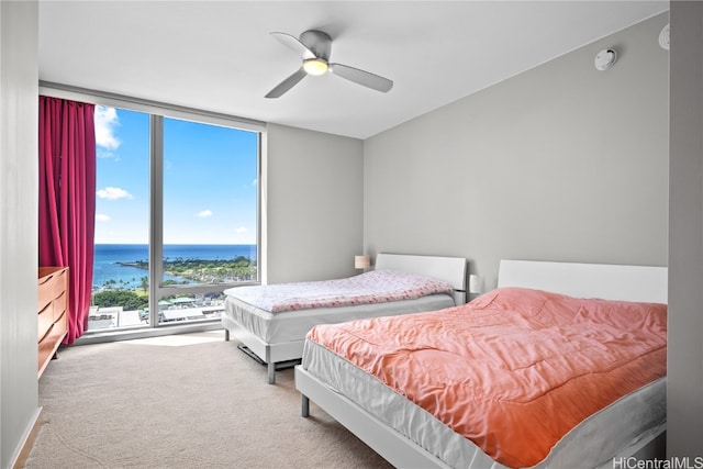 carpeted bedroom featuring a water view and ceiling fan