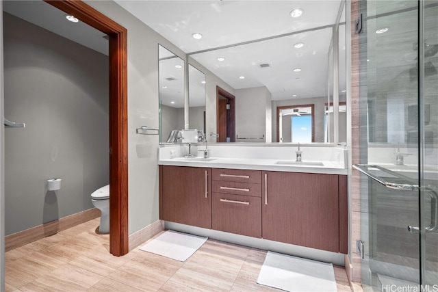 bathroom featuring toilet, a shower with shower door, and vanity