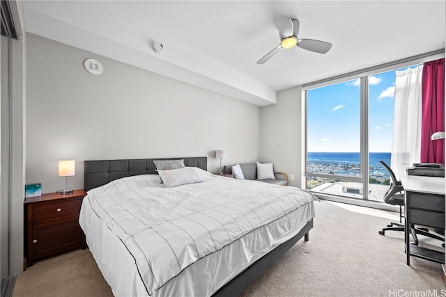 bedroom featuring multiple windows, a water view, light colored carpet, and ceiling fan