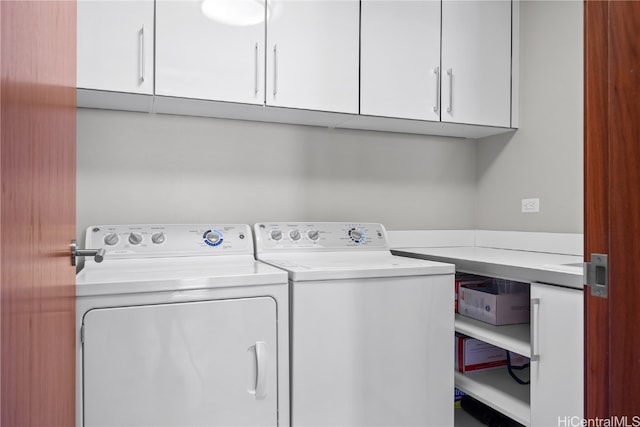 clothes washing area featuring washing machine and clothes dryer and cabinets