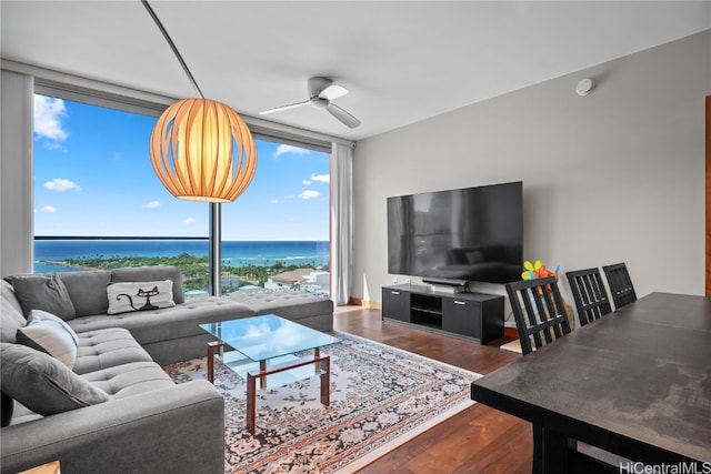 living room featuring ceiling fan, dark wood-type flooring, a water view, and a wealth of natural light