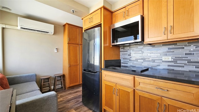 kitchen featuring tasteful backsplash, dark hardwood / wood-style flooring, an AC wall unit, refrigerator, and black cooktop