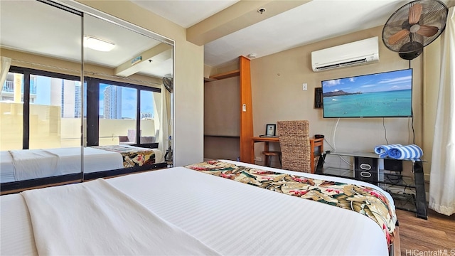 bedroom featuring beam ceiling, hardwood / wood-style flooring, and a wall mounted AC