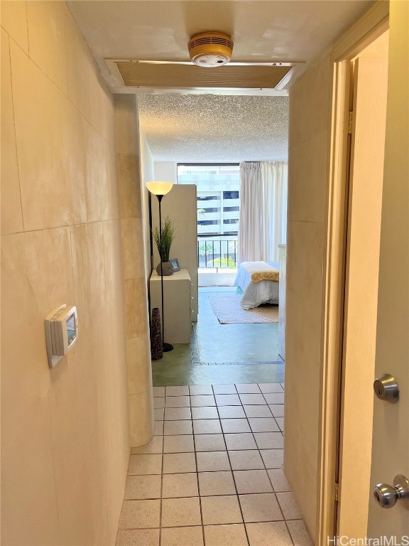 hall with light tile patterned flooring, tile walls, and a textured ceiling