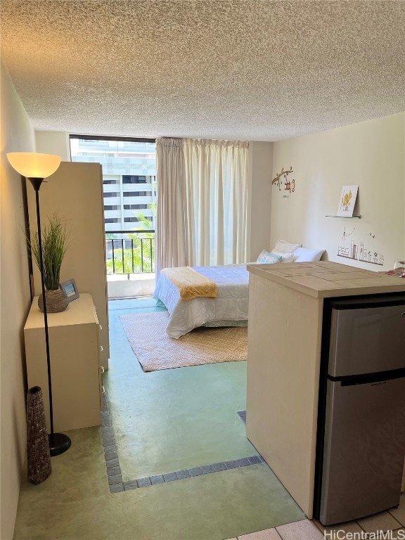 unfurnished bedroom with stainless steel fridge, a textured ceiling, and a wall of windows