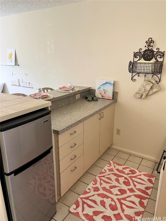 interior space featuring light tile patterned flooring, cream cabinets, and stainless steel refrigerator