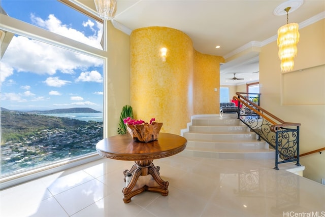 interior space with a mountain view, tile patterned floors, ornamental molding, and ceiling fan with notable chandelier