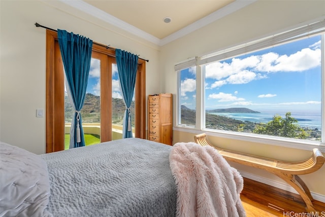 bedroom with ornamental molding, a water view, and hardwood / wood-style flooring