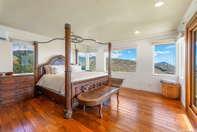 bedroom featuring ornamental molding, a wall unit AC, and hardwood / wood-style floors