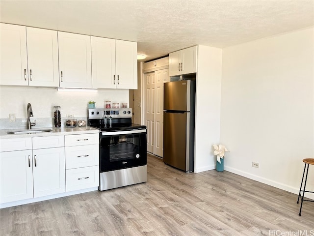 kitchen with light hardwood / wood-style flooring, sink, white cabinets, appliances with stainless steel finishes, and a textured ceiling