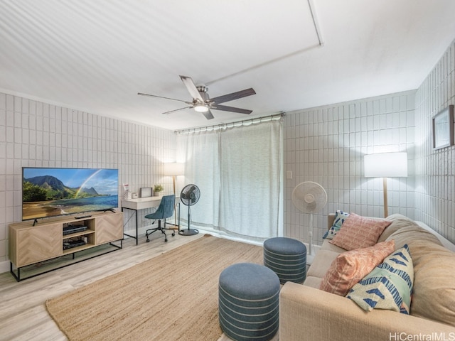 living room featuring tile walls, wood-type flooring, and ceiling fan