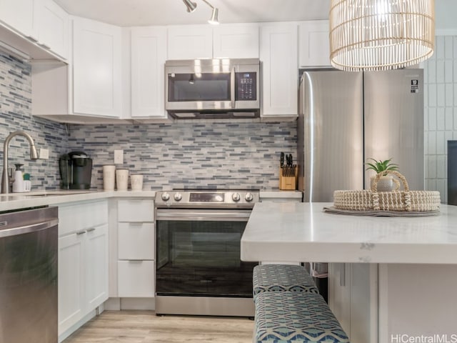 kitchen with decorative backsplash, light hardwood / wood-style flooring, white cabinetry, and stainless steel appliances