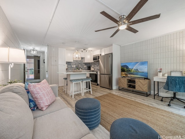 living room featuring tile walls, light hardwood / wood-style flooring, and ceiling fan