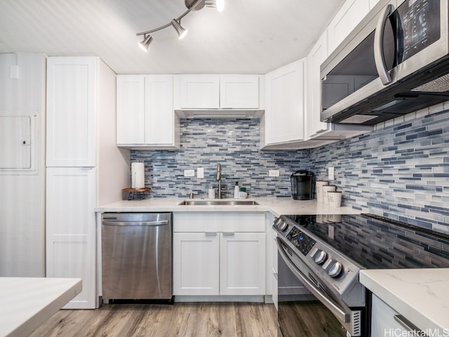 kitchen with white cabinets, tasteful backsplash, light hardwood / wood-style flooring, sink, and stainless steel appliances