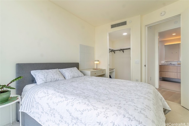 carpeted bedroom with sink, a walk in closet, a closet, and ensuite bath