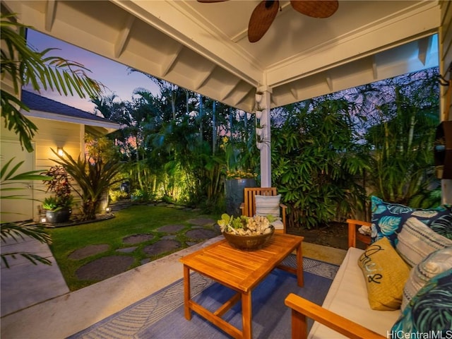 patio terrace at dusk featuring an outdoor living space, ceiling fan, and a lawn