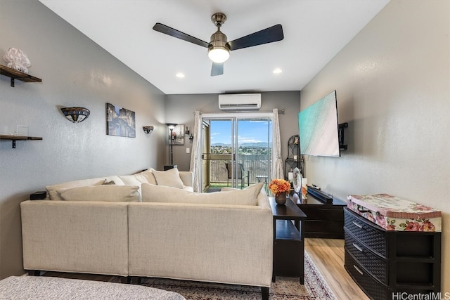 living room featuring a wall mounted air conditioner, ceiling fan, and light hardwood / wood-style flooring